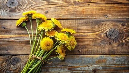Fototapeta premium Rustic Wooden Background Featuring a Small Bouquet of Bright Yellow Dandelions Tied with Twine