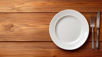 White plate with knife and fork on wooden table