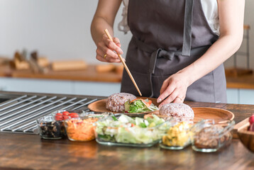 キッチンでワンプレートランチを盛り付ける主婦の手元

