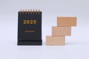 2025 calendar and stack of wooden blocks on white background
