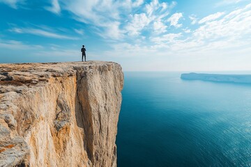 Man standing on cliff edge overlooking ocean.