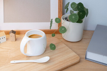 Coffee cup with small plant pot and on wooden table