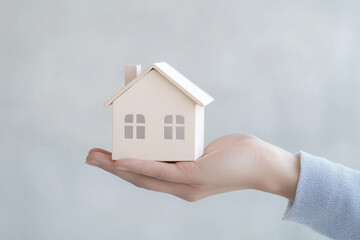 Hand Holding Miniature House Model on White Background