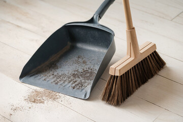 Dustpan and Broom on Clean Wooden Floor