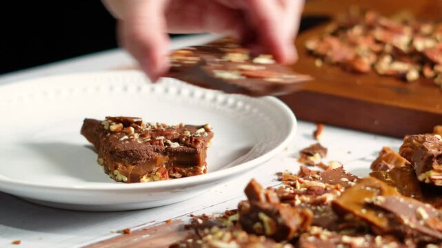 Making chocolate toffee bark with fresh roasted pecans for dessert.  Candy bark made of toffee, chocolate and nuts  broken up into pieces.
