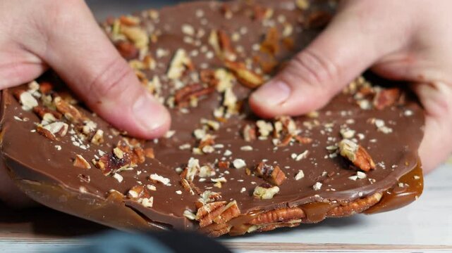 Making chocolate toffee bark with fresh roasted pecans for dessert.  Candy bark made of toffee, chocolate and nuts  broken up into pieces.