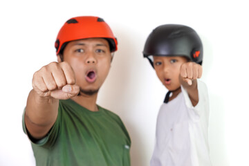 selective focus, A asian father and son show excitement with their fists raised, wearing helmets.