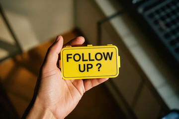 Hand Holding Smartphone Displaying Follow Up Message in Bold Yellow Text