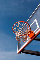 Closeup red basketball hoop and a blue sky in the city park. 