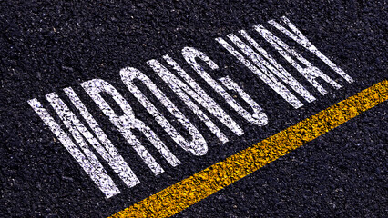 Obraz premium Wrong way, wrong way text written and yellow line on asphalt road ground.
