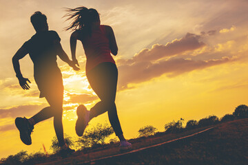 Silhouette of young couple running together on road across the bridge. Couple, fit runners fitness...