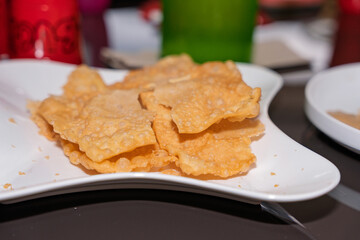 A white plate filled with hojuelas, a traditional Colombian festive treat capturing the golden, crispy texture of this dish, perfect for themes of local cuisine, traditional celebrations and culture