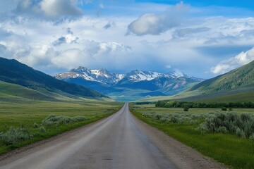 Scenic mountain road stretching towards snow-capped peaks under a partly cloudy sky. (1)