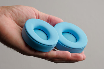 Blue headphones earpads in hands, showcasing changing replacement ear pads ear cushion.