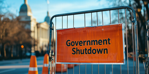 A bright orange "Government Shutdown" sign displayed on a metal barricade near a government building, highlighting restricted access and closure