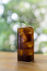 Black coffee with ice cubes on wood table