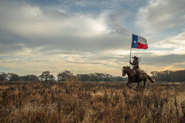 Woman Wearing Cowboy Hat Riding Running Horse While Holding Large Texas Flag In Grassy Field With...
