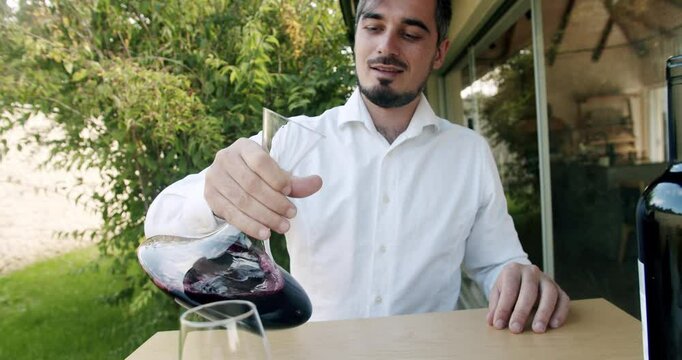 A sommelier shakes the red wine in a decanter in slow motion. Man winemaker tasting wine. Cleaning the wine of deposits and odors, before it is served. Winemaking concept.