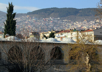 Photo with part of the Koza Han building in the historical part of the city with the mountain in the background in the city of Bursa, Turkey © Kateryna M