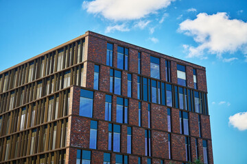 Office building with brick facade and large glass windows under blue sky. Contemporary...