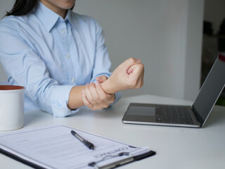 Young Asian woman feels numbness and severe pain in her wrist Caused by sitting and working for a...