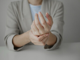 Young Asian woman feels numbness and severe pain in her wrist Caused by sitting and working for a...