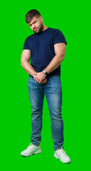 Man standing with a thoughtful expression in a casual outfit against a green background © fotofabrika