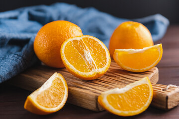Sliced oranges fruit near denim textile on wooden board. Orange juicy fruit, citrus minimal concept