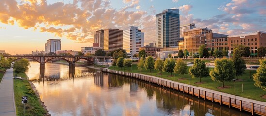 Fototapeta premium Scenic sunrise cityscape over river with bridge and park.