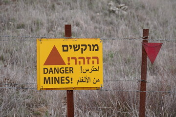 signs of landmines on barbed wire fence on Israeli Golan Heights