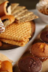 Variety of baked treats displayed on a wooden board with a bowl of snacks at a cozy setting during the afternoon