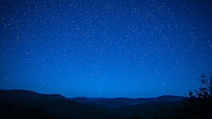 A dazzling starry sky lights up a tranquil landscape, filled with countless shimmering stars on a deep blue backdrop, evoking the enchantment of the night.