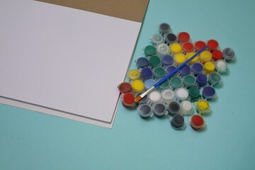 Colorful Acrylic Paint Set with Brush and Paper on Blue Background