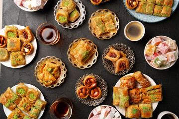Traditional Middle Eastern sweets served on various plates with drinks in a cozy setting during a festive gathering