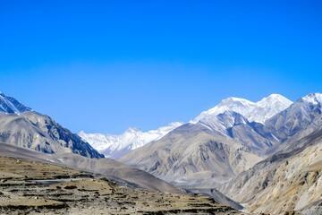 Majestic mountain landscape with snow-capped peaks under a vibrant clear blue sky.