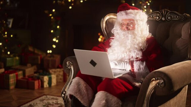 Traditional Christmas and modern technology, Santa Claus using laptop at home. Portrait of old wizard with portable computer on laps, shopping online and chatting in social media, emotional Santa