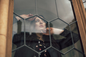 woman looking through the window. It is located indoors, and the photo was taken outside. The...