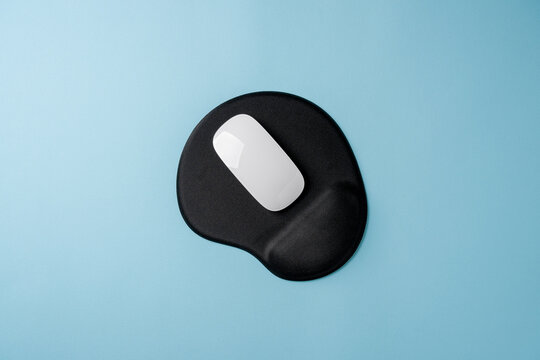 Top view of modern white mouse on black mousepad on blue table