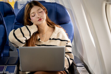 Exhausted Asian woman in casual clothes feeling dizzy or airsick while working on laptop during flight