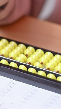 そろばん(珠算)をする小学生のクローズアップ　顔無しの手元のクローズアップの縦動画