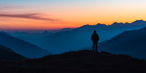 Fototapeta premium Silhouette of a man against the stunning backdrop of sunrise in the mountains, capturing the serene beauty and tranquility of nature as the day begins among the mountain peaks.