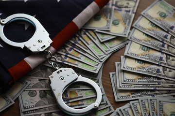 Handcuffs with US Flag and Piles of Dollars Reflecting Financial Crime and Law Enforcement