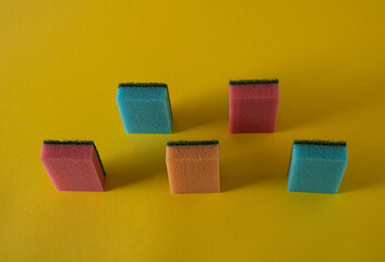 On a sunny summer day, blue, pink and orange colored sponges dry after cleaning a dirty and dusty surface.