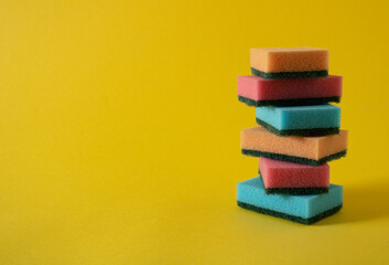 Blue, pink and orange small sponges left untidy after hard cleaning of dust and dirt on a yellow kitchen floor