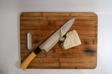 Blue cheese and a big knife on a brown wooden cutting board