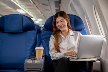 A confident, attractive Asian businesswoman sits on the plane, flying abroad for a business meeting.