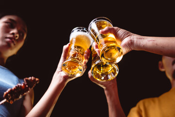 A man's and woman's hands raise beer glasses group in a lively night party, surrounded by family and friends. The evening is filled with warmth, laughter, and joyful celebration.