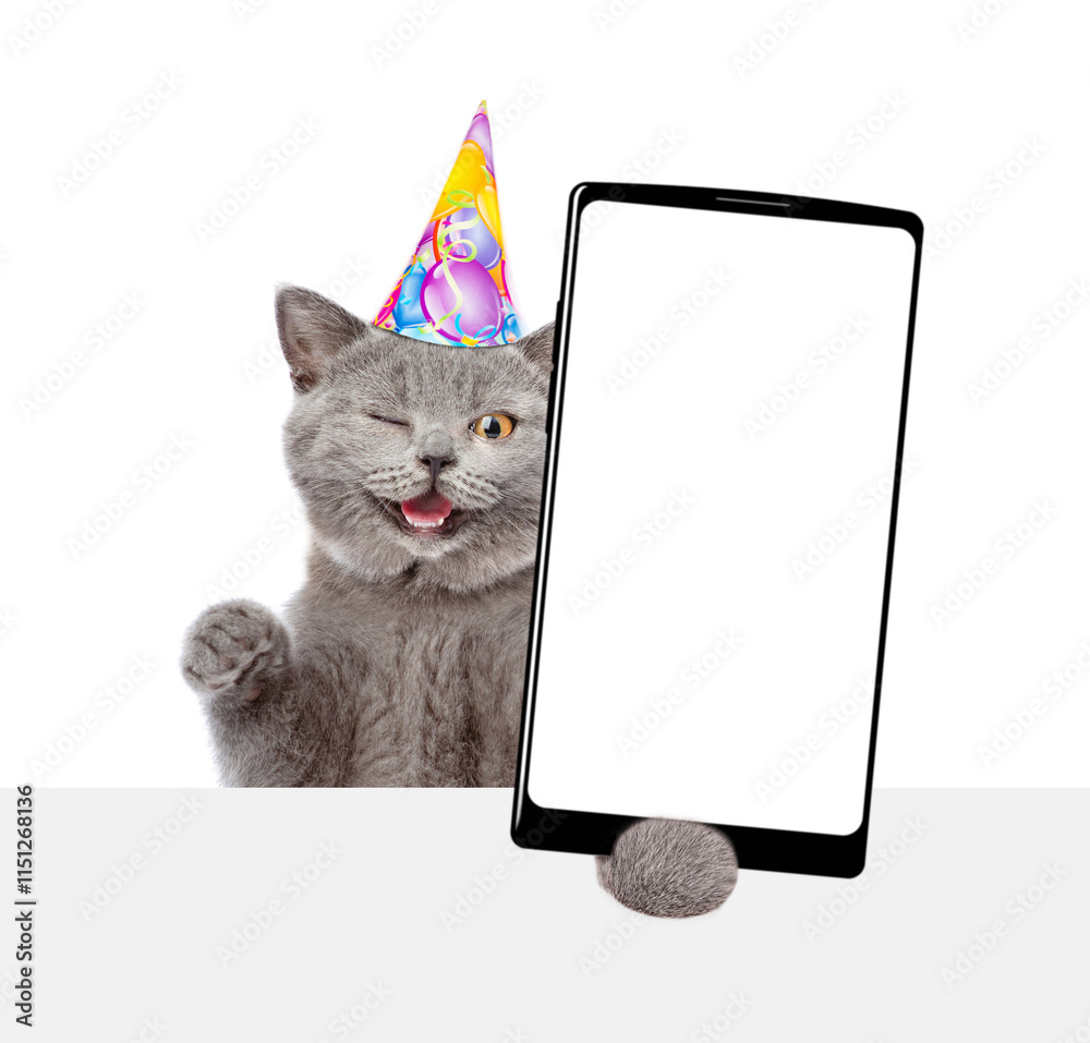 Poster Winking cat wearing party cap shows big smartphone with blank screen above empty white banner. Empty space for text. isolated on white background