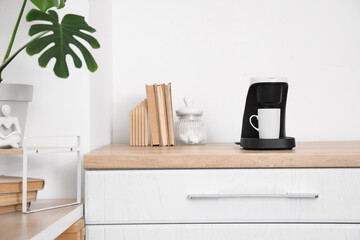 Coffee machine with cup and books on counter in kitchen
