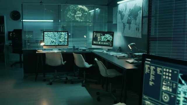 Pan shot of satellite surveillance software scanning urban areas on multiple computer and multimedia screens at intelligence agency office, in blue light, after working hours at nighttime
